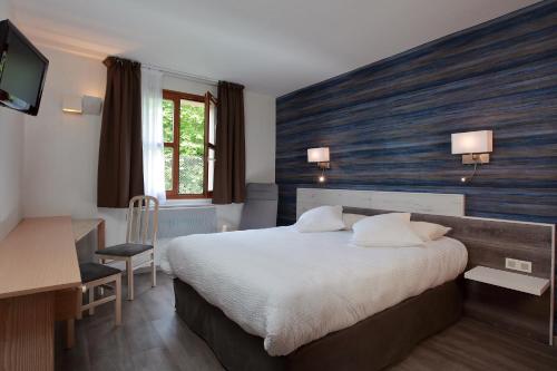 een hotelkamer met een groot bed en een bureau bij Logis Le Luth in Mirecourt