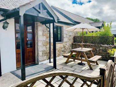 a patio with a picnic table and an umbrella at Hallagenna Cottages in Bodmin