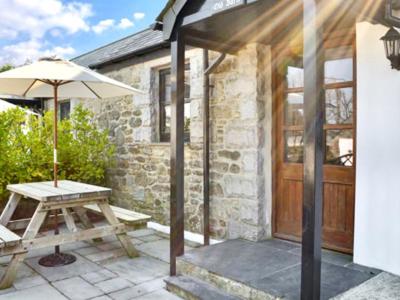 a patio with a picnic table and an umbrella at Hallagenna Cottages in Bodmin