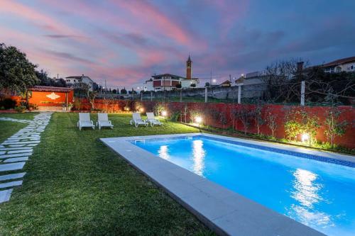 a backyard with a swimming pool with chairs and a fence at Casa dos Mortágua in Fermelã