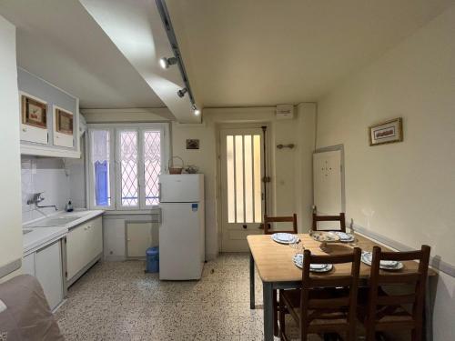 une cuisine avec une table et un réfrigérateur blanc dans l'établissement 3LIB7 - au cœur du faubourg de Collioure appartement pour 3 personnes, à Collioure