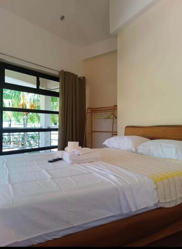 ein Schlafzimmer mit einem großen weißen Bett mit einem Fenster in der Unterkunft Tyner's Place in Panglao