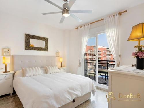 a white bedroom with a bed and a balcony at Apartment with pool and private parking near Aqua Mijas in Fuengirola