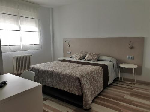 1 dormitorio con cama, mesa y ventana en Hotel Area Serrano, en Buniel
