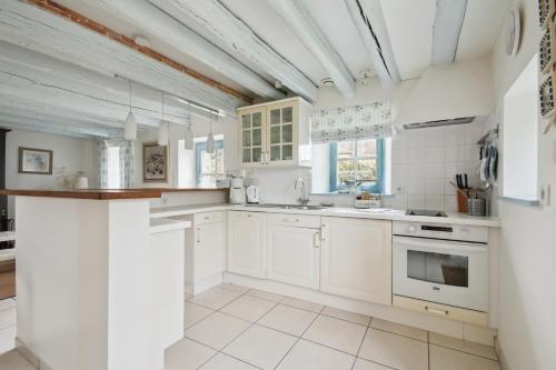 une cuisine avec des armoires blanches et des appareils électroménagers blancs dans l'établissement Gite Bleu, à Missillac