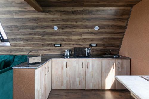 a kitchen with wooden walls and a counter with a sink at StayVista at The Loft - A Frame structure & English Interiors in Srinagar
