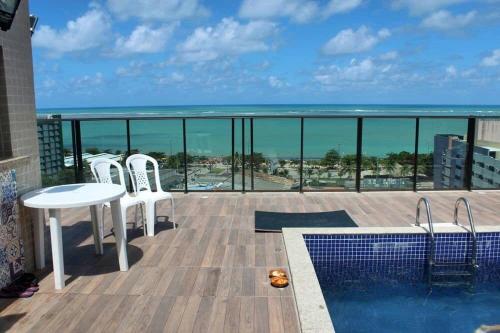 balcón con mesa, sillas y vistas al océano en Grande Apartamento 2/4 Beira-Mar, en Maceió