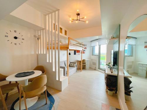 サンフェルナンドにあるGBU's Studio with Balcony at Azure North Pampangaの二段ベッド、テーブル、椅子が備わる客室です。
