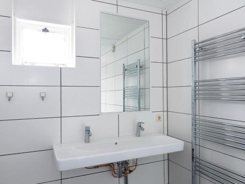 ein weißes Badezimmer mit Waschbecken und Spiegel in der Unterkunft Holiday home with sauna, outdoor spa in Earnewâld