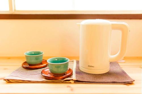 a tea kettle and two cups on a table at Osaka SENJU big Tatami house Max 16ppl direct to KIX airport in Osaka