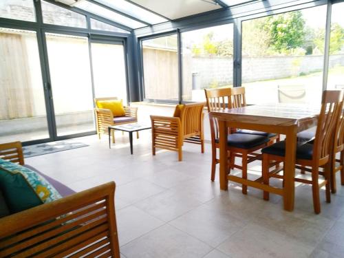 a dining room with a table and chairs and windows at L'Embrun de la Baie de Somme in Saint-Valery-sur-Somme