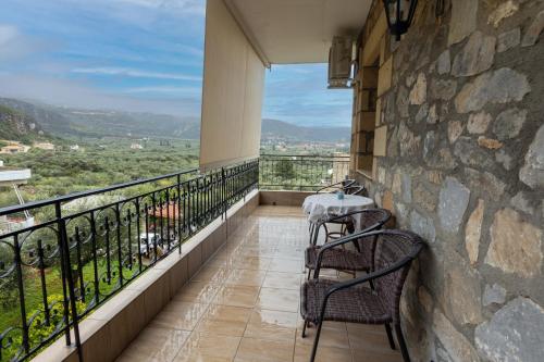 a balcony with two chairs and a table on a stone wall at Paradeisos in Kardamili
