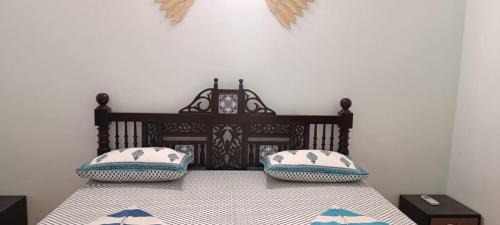 um quarto com uma cama com duas almofadas em Lairai's Happy Home em Candolim