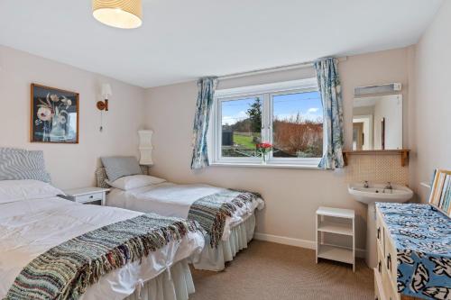 a bedroom with two beds and a window and a sink at Finest Retreats - Harbour House in Craster