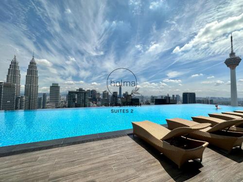 una piscina con sillas y un perfil urbano en The Platinum 2 Kuala Lumpur by HOLMA, en Kuala Lumpur