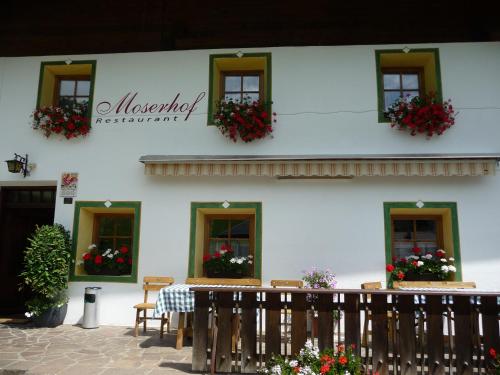 a white building with windows with flower boxes on them at Berggasthaus Agritur Moserhof in Braies