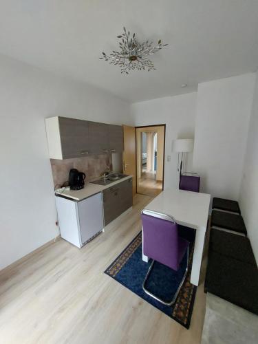 a kitchen with a table and purple chairs in a room at Pension Hofer in Bad Berneck im Fichtelgebirge