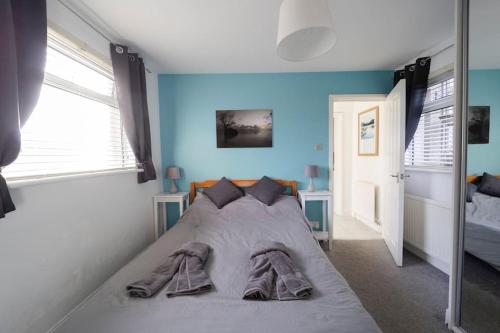 Bett in einem Schlafzimmer mit blauer Wand in der Unterkunft Modern Flat in Porthcawl in Porthcawl