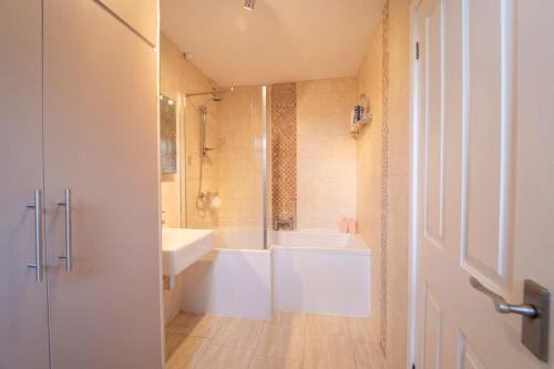 a bathroom with a white tub and a sink at Modern Flat in Porthcawl in Porthcawl