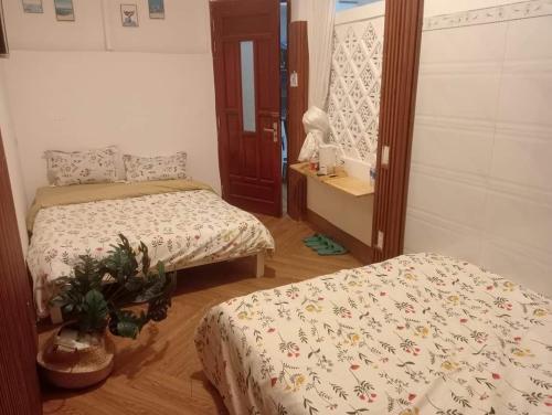 a bedroom with two beds and a table with a plant at Nhà bốn chín in Ấp Khánh Phước (1)