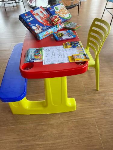 a red and yellow table with books and a chair at POUSADA DOS LAGOS in Paulino Neves