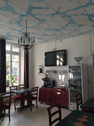 une salle à manger avec une table et une télévision au plafond dans l'établissement Hôtel De Paris, à Charleville-Mézières