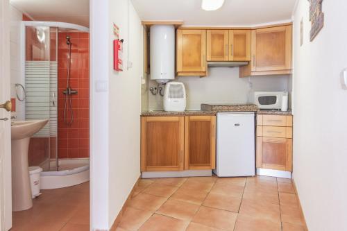 - une cuisine avec des placards en bois et un réfrigérateur blanc dans l'établissement Estúdios Lagido - Peniche Surf Camp Working Space & surf, à Ferrel