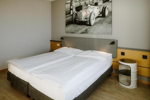 a bedroom with a bed with a picture of a car on the wall at Hotel A1 Grauholz in Bern