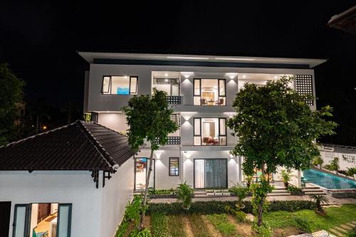 a white house with a pool at night at Golden Star Villa Hoi An in Hoi An