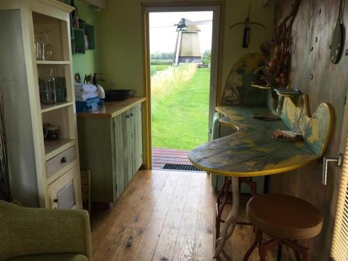 eine Küche mit einem Tisch und Blick auf eine Windmühle in der Unterkunft de Veldwachter in 't Zand
