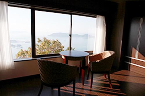 a room with a table and chairs and a large window at Hotel Bokaiso in Takamatsu