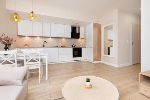 a kitchen and living room with white cabinets and a table at Beaufort Estate Apartment by Renters in Gdynia
