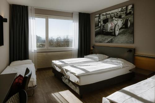 1 dormitorio con 2 camas y una foto de coche en Hotel A1 Grauholz, en Berna