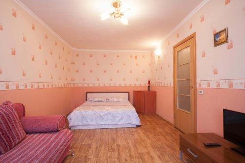 a bedroom with a bed and a couch and a tv at Kvartirov Apartment at Surikova in Krasnoyarsk