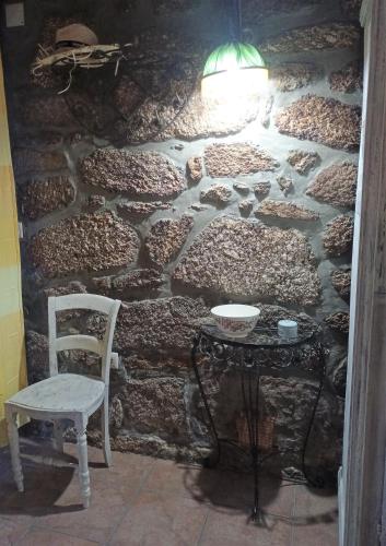 a stone wall with a table and a chair at Casas do Durão-Memories House in Lajeosa