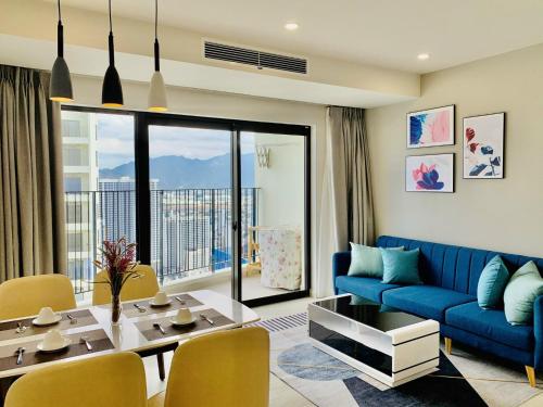 Gold Coast Luxury Apartment Nha Trang في نها ترانغ: غرفة معيشة مع أريكة زرقاء وطاولة