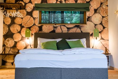 un letto con cuscini verdi in una stanza con tronchi di bergwaldsee a Velden am Wörthersee