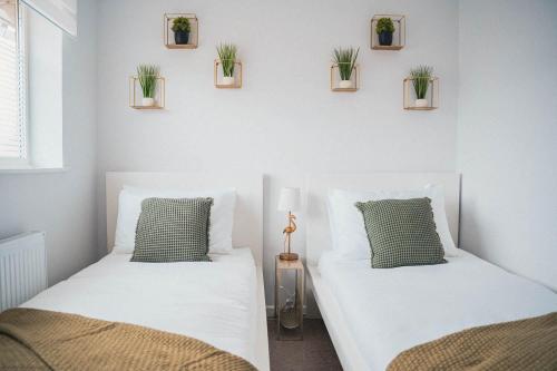 two beds in a room with plants on the wall at 2 Bed House, Sleeps 6, Dog Friendly, Close to A14 M11, with Garden & Parking LONG STAY WORK CONTRACTOR LEISURE, JADE in Cambridge