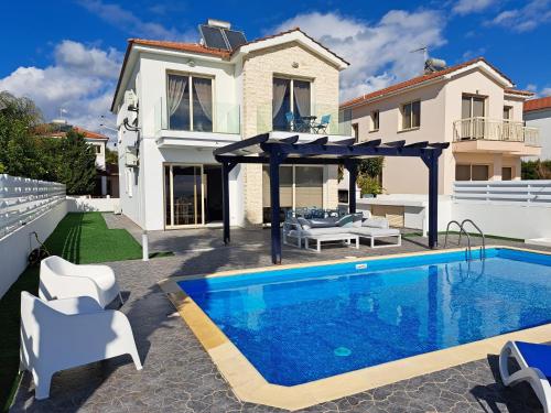 a villa with a swimming pool in front of a house at Villa Waves in Mazotos