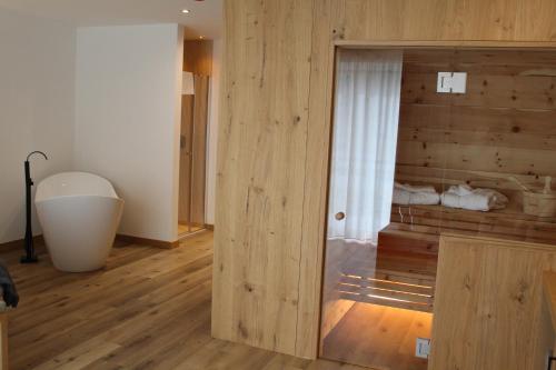 a room with a wooden wall and a room with a tub at B&B Relais Dolomiti in Bedollo