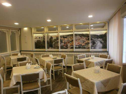 a restaurant with white tables and chairs and paintings at Dnepropetrovsk Hotel in Dnipro