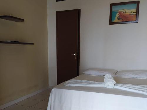 a bedroom with a white bed with a brown door at Pousada Via Lactea in Canoa Quebrada