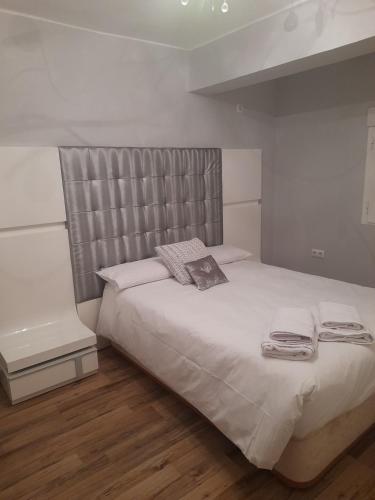 a bedroom with a large white bed with a headboard at PISO RONDA in Granada