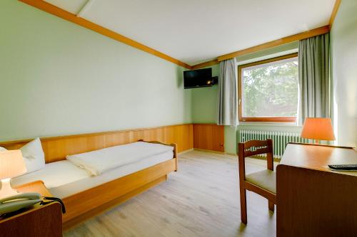 a bedroom with a bed and a desk and a window at Hotel Hannover Airport by Premiere Classe in Hannover