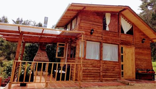 Cabaña de madera con porche y puerta en La Arboleda, en Tilatá