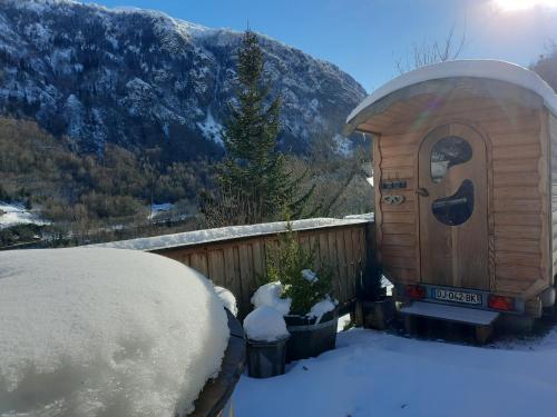 ein kleines Haus mit Schnee auf dem Boden neben einem Zaun in der Unterkunft Roulotte Ancolie in Gèdre