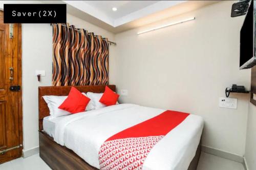 a bedroom with a large bed with red pillows at Hotel Renuka in Visakhapatnam