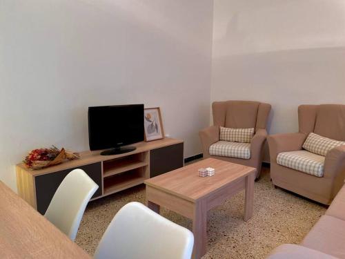 sala de estar con TV, 2 sillas y mesa en Can Jaume. Casa céntrica y cerca de la naturaleza. en Arbúcies