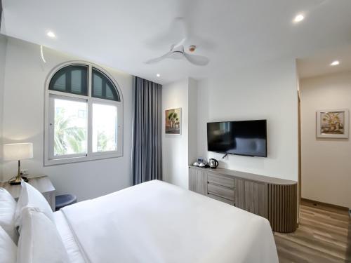 biała sypialnia z dużym łóżkiem i telewizorem w obiekcie Anna Beach Phú Quốc w Duong Dong