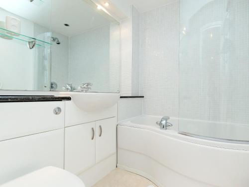 La salle de bains blanche est pourvue d'une baignoire, d'un lavabo et d'une douche. dans l'établissement Beachlands, à Llanelli